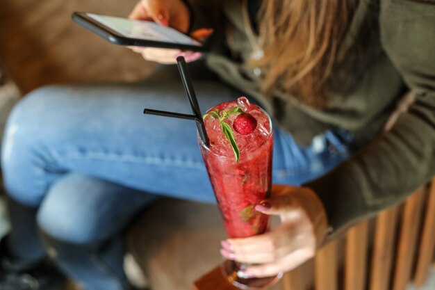 Side view woman drinking strawberry cocktail with black straws