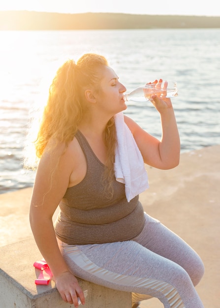 運動後の湖のほとりで水を飲む女性の側面図