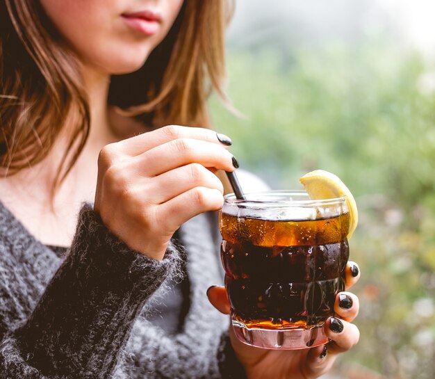 女性がレモンのスライスでさわやかなカクテルを飲む側面図