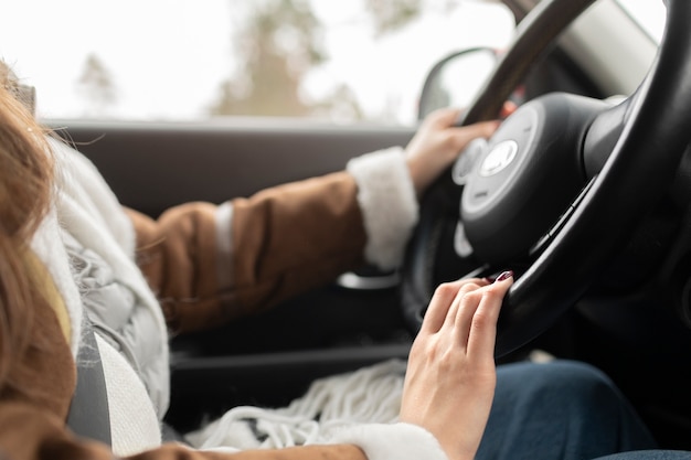 Side view of woman driving a car for a winter road trip