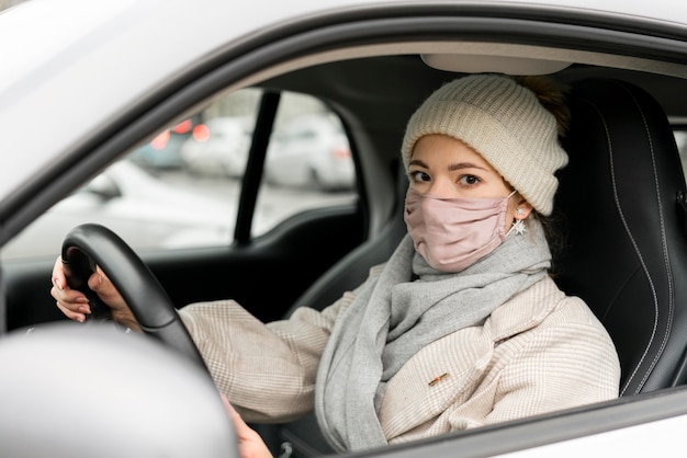 Free photo side view of woman driving with medical mask