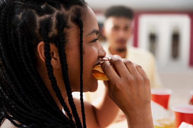 Side view woman eating burger outdoors
