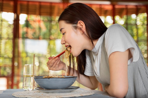 Side view woman eating delicious noodles