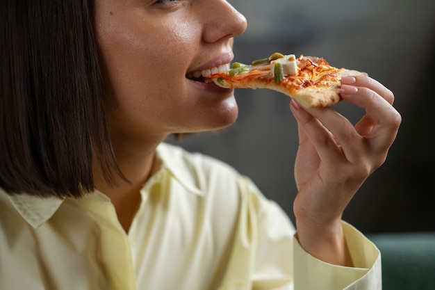 Foto gratuita donna di vista laterale che mangia pizza deliziosa