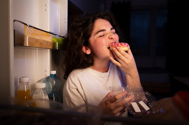 Вид сбоку женщина ест пончик