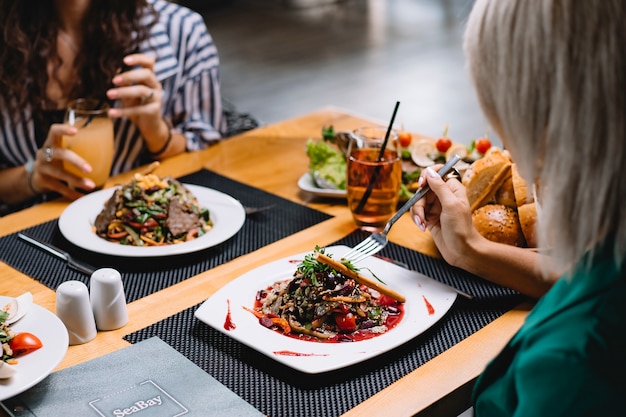 Foto gratuita la vista laterale di una donna che mangia l'insalata della verdura fresca è servito con olio d'oliva alla tavola