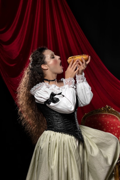 Foto gratuita donna di vista laterale che mangia hot dog