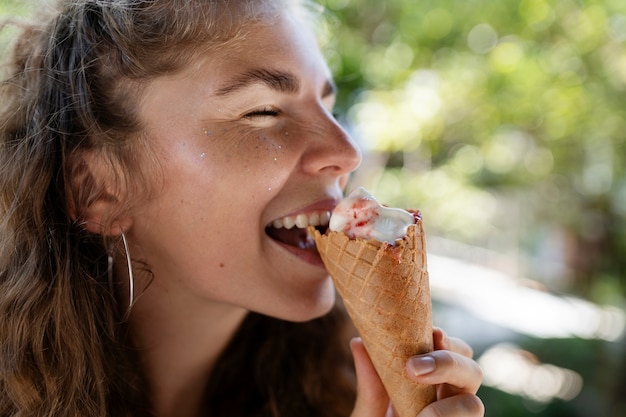 Foto gratuita donna di vista laterale che mangia il cono gelato