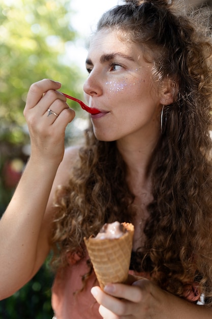 Free photo side view woman eating ice cream with spoon