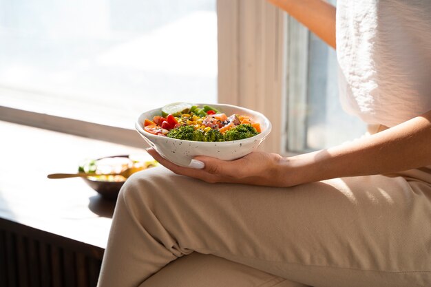 Free photo side view woman eating salmon bowl