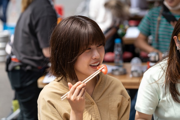 Free photo side view woman eating with chopsticks