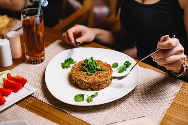 Side view a woman eats barbecue salad with herbs and juice