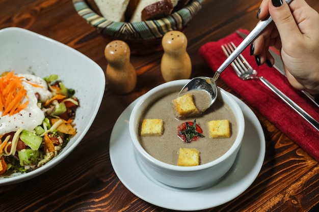 Foto gratuita la donna di vista laterale mangia la zuppa di fungo con il pomodoro e i cracker in un piatto