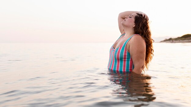 ビーチで水で彼女の時間を楽しんでいる女性の側面図