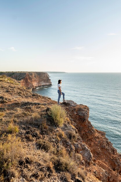 Side view woman enjoying the view on a coast