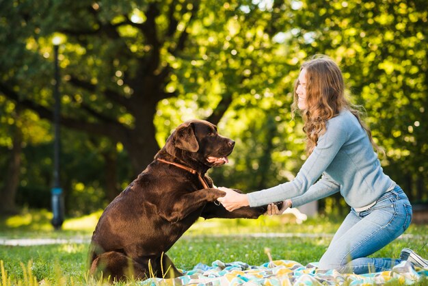 Side view of a woman enjoying with her dog in garden