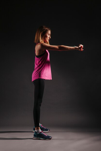 Free photo side view woman exercising in dark room