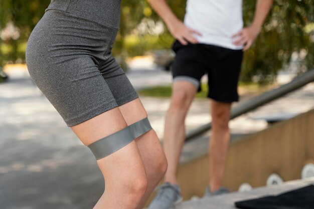 Side view of woman exercising outdoors with elastic band