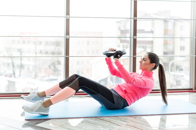 Side view of woman exercising with weight plate