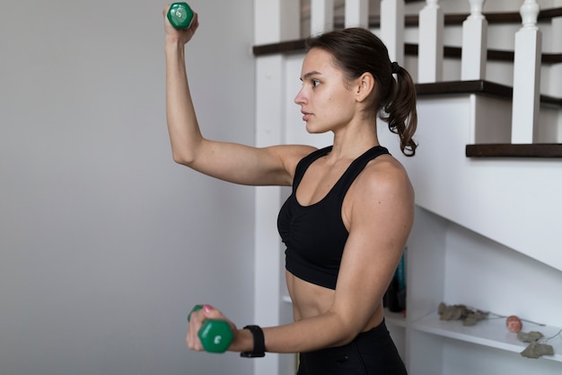 Вид сбоку женщины сгибание рук во время тренировки с весами