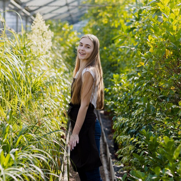 Side view woman between greenhouse foliage