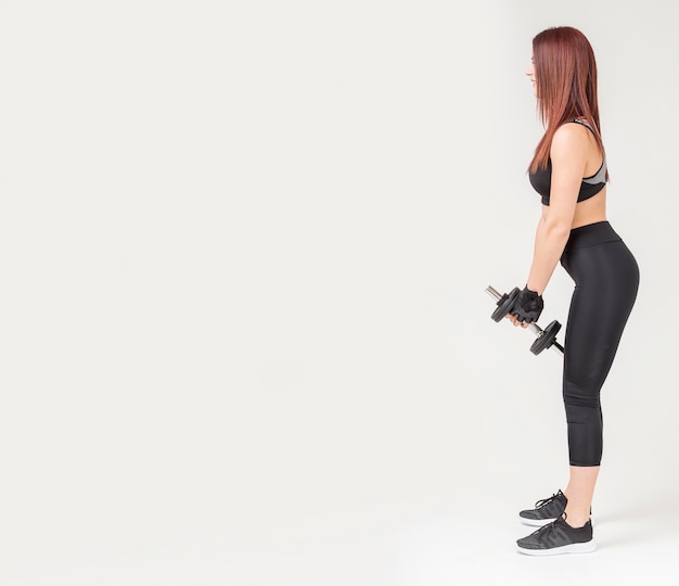 Side view of woman in gym attire holding weight