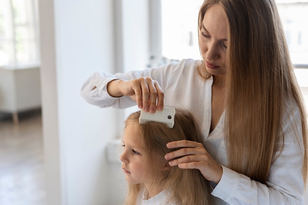 Free photo side view woman helping girl with lices