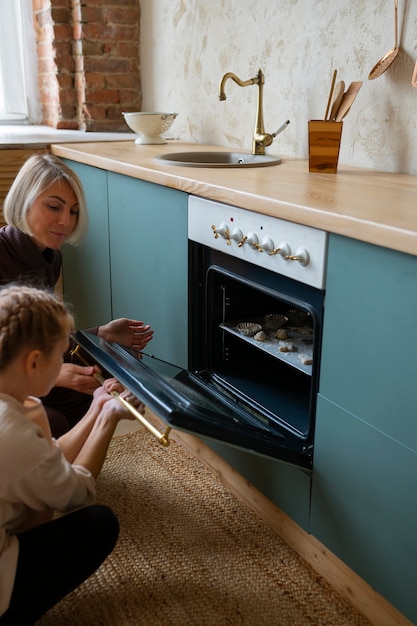 Side view woman helping girl with the oven