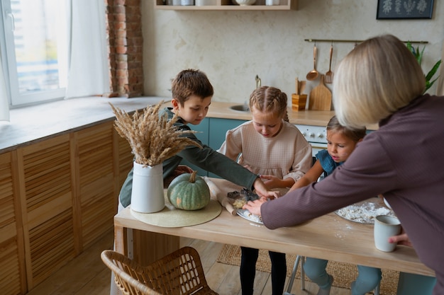 Free photo side view woman helping kids cook