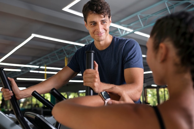 Free photo side view woman helping man workout at gym