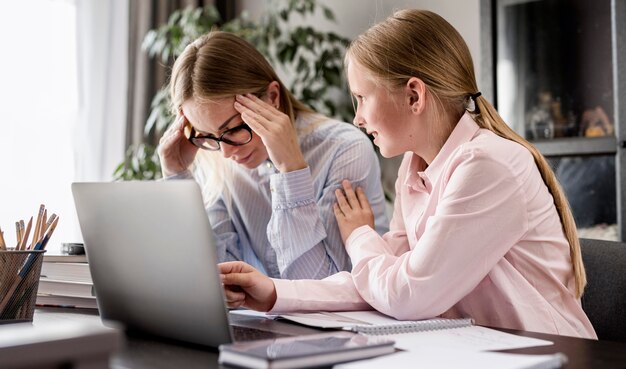 Side view woman helping young girl with homework