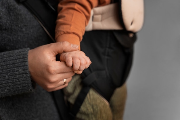 Free photo side view woman holding baby in carrier