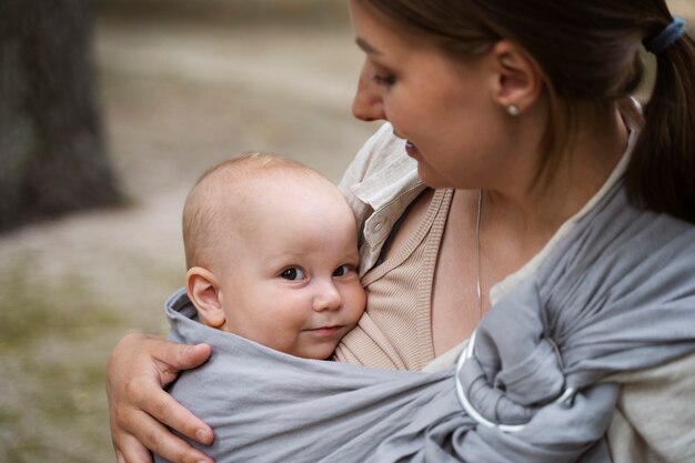 屋外で赤ちゃんを抱いている側面図の女性