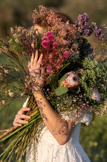 아름 다운 꽃 꽃다발을 들고 측면 보기 여자