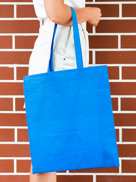 Side view woman holding a blue bag mock-up