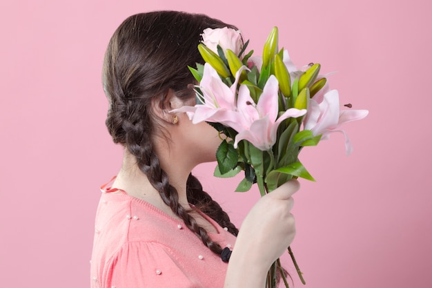 Free photo side view of woman holding bouquet of lilies over face