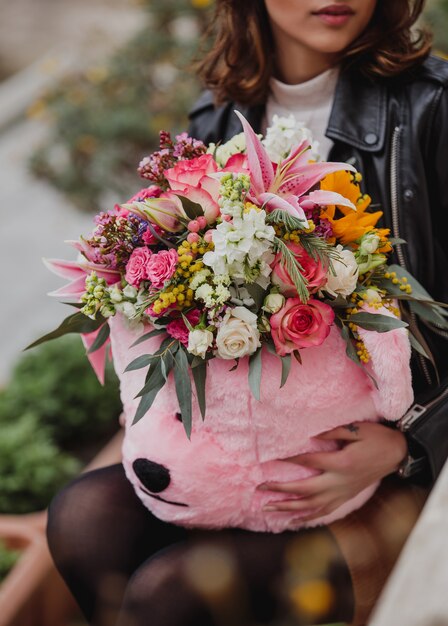 Side view of a woman holding a bouquet of pink and white color roses with pink color lilies mimosa eustomas pink color spray roses and greenery