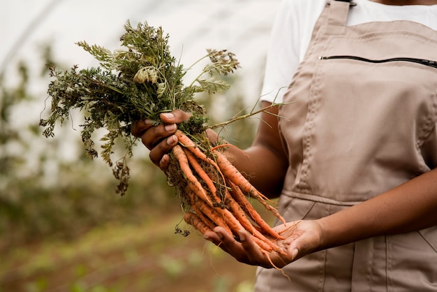 Free photo side view woman holding carrots