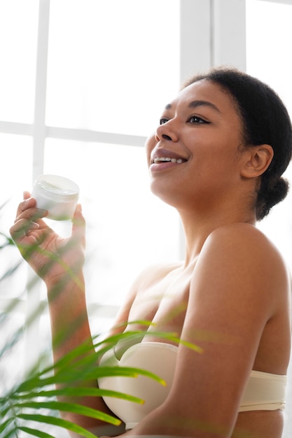 Free photo side view woman holding cream container