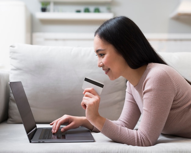 Side view of woman holding credit card and ordering online