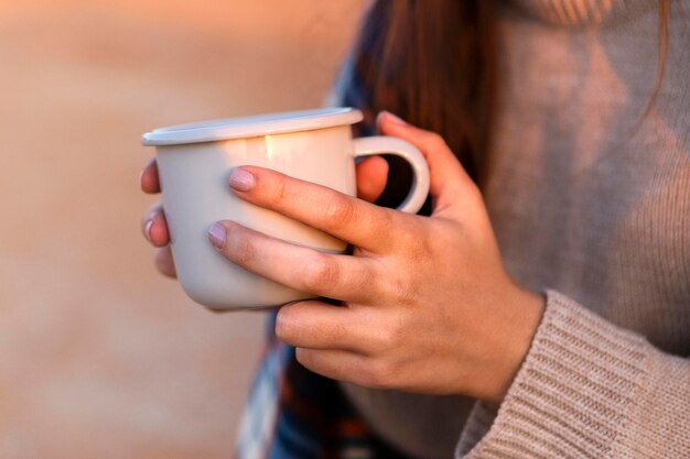 自然の中で屋外ながら一杯のコーヒーを保持している女性の側面図