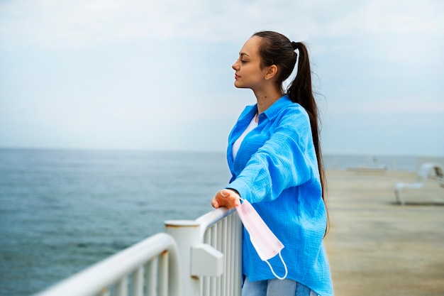 Side view woman holding face mask