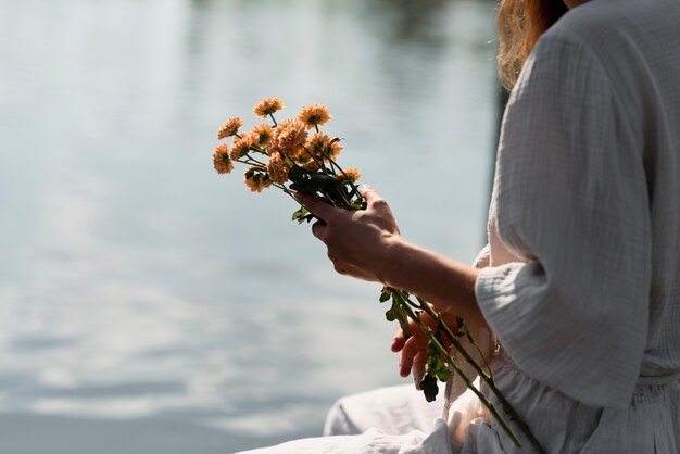 花の花束を保持している側面図の女性