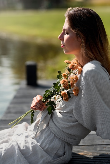 Foto gratuita mazzo di fiori della holding della donna di vista laterale