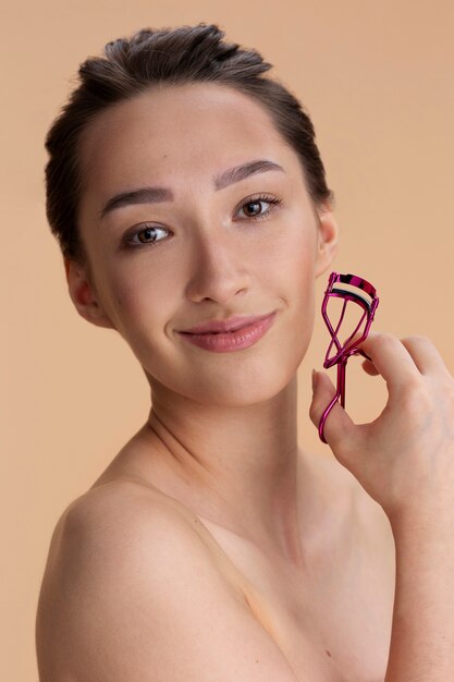 Free photo side view woman holding lash curler