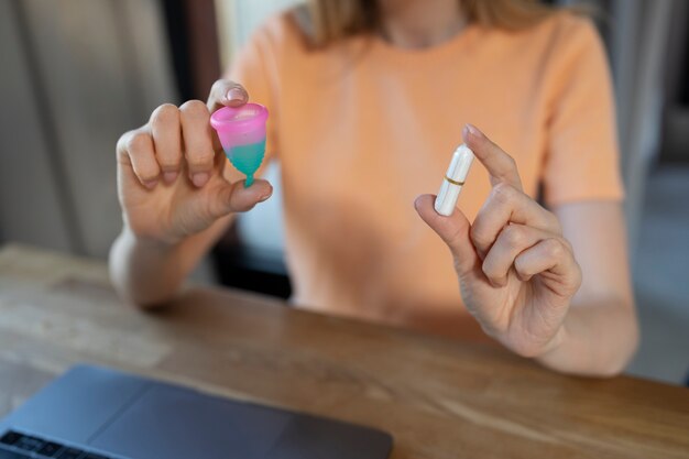 Side view woman holding menstrual cup and tampon