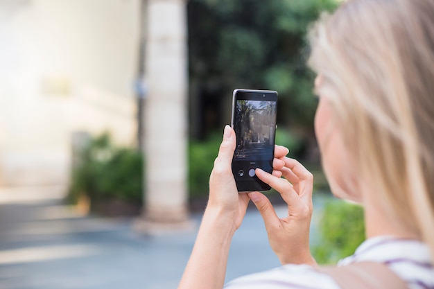 Side view of woman holding mobile taking photograph