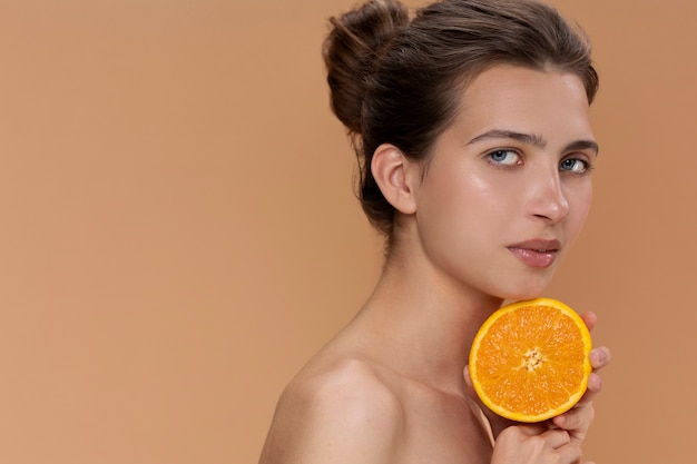 Free photo side view woman holding orange half