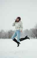 Free photo side view of woman holding smartphone and jumping in the air outdoors