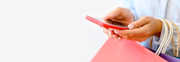 Side view of woman holding smartphone and shopping bags for cyber monday